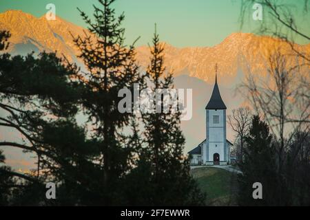 Fantastische charmante St. Primoz Kirche auf einem kleinen Hügel mit bunten Bergkulisse im Hintergrund bei Sonnenuntergang, Jamnik Dorf, Slowenien, Europa mit Stockfoto