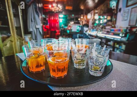 Aperitif-Drinks und Shots warten auf einem Servierbrett in einer Bar, die auf die ersten Gäste bei einer Parade wartet. Partyatmosphäre und ein paar Drinks im Vordergrund Stockfoto