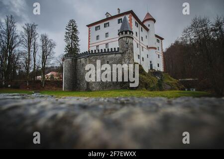 Blick auf die Burg Sneznik im Spätherbst und Blick über die Steinmauer. Schönes weißes Schloss, das über die Wasserbarriere ragen. Stockfoto