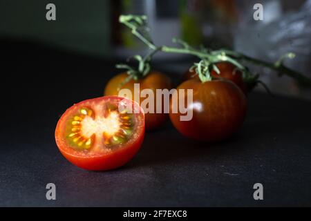 Tomate in Scheiben geschnitten auf einem Zweig isoliert auf schwarzem Hintergrund Stockfoto