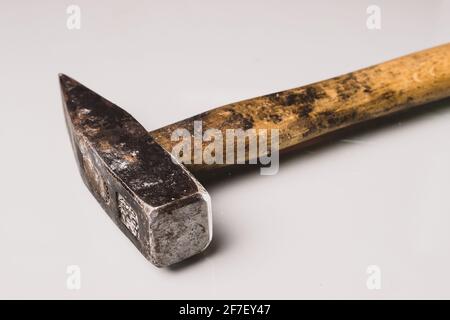 Ein gebrauchter und abgenutzter hammer im europäischen Stil mit Holzgriff und Metallspitze. Isoliert auf weißer reflektierender Platine. Stockfoto