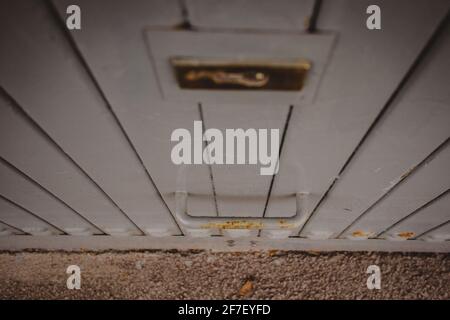 Metallgriff an einem Garagentor in grauer Farbe. Ein etwas rostiger Metallhalter an einem geschlossenen grauen Garagentor. Stockfoto