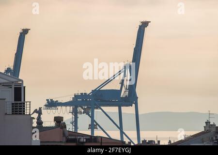 Blauer Frachtkran in einem Hafen an einem sonnigen, trüben Herbsttag. Wohnhäuser im Vordergrund. Stockfoto