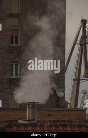 Dampf oder Dampf, der sichtbar aus einem neuen Edelstahlkamin auf dem Gebäude aufsteigt. Stockfoto