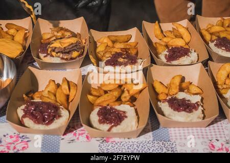 Zubereitung von Gourmet-Burgern oder Hamburgern mit Kartoffeln, Speck, Käse, Brötchen. Detail von halbgemachten Burgern in Pappkartons Stockfoto