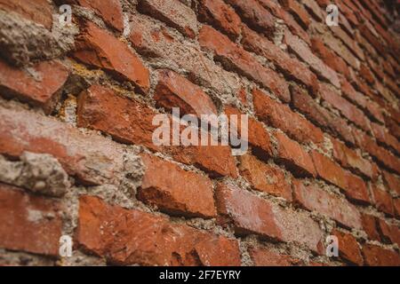 Detail der alten Ziegelwand mit sichtbaren Zementflecken und Resten auf den Ziegel. Rote Backsteinmauer aus der Nähe betrachtet. Stockfoto