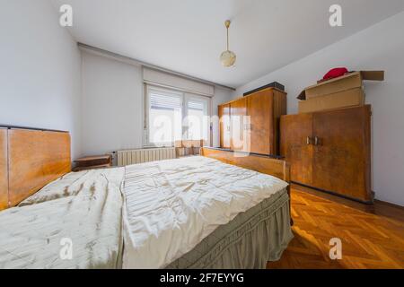 Altes Schlafzimmer aus Holz in einem alten Haus. Sichtbares altes Bett, Kleiderschränke und kleine Nachttische. Stockfoto