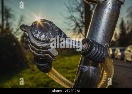 Detail eines billigen, abgenutzten Zahlenschllosses auf einem alten Fahrrad, mit Sonnenstreifen oder Lichtreflexen direkt hinter dem Schloss. Parkanlage oder außerhalb in einem Vorort von A Stockfoto