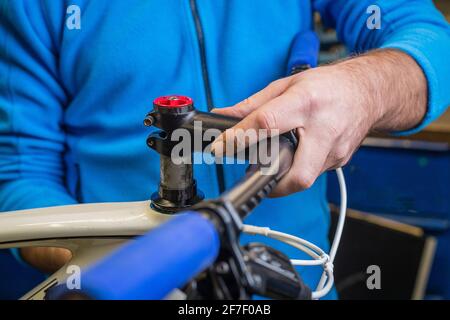 Fahrradmechaniker, der einen Fahrradvorbau an einem Gabelrohr als Teil einer Fahrraddienstleistung montiert. Service-Mann repariert vorderen Teil eines Mountainbikes. Stockfoto