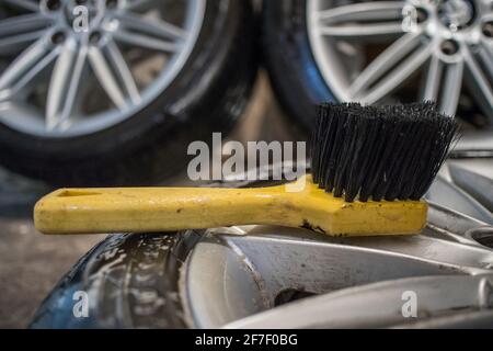 Reinigung von Leichtmetallfelgen oder Leichtmetallfelgen eines Autos mit einer gelben Bürste. Hartnäckigen Bremsstaub mit einem Reinigungslösemittel und einer bru reinigen Stockfoto