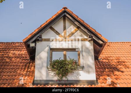 Detail eines einzelnen alten Dachfensters auf einem älteren ländlichen Vintage-Haus mit roten Schindeln. Sogenannter Dachgauber. Stockfoto