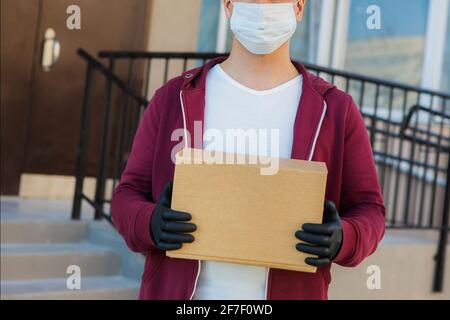 Kurier in medizinischen Gummihandschuhen und Schutzmaske mit Kartons. Lieferservice. Quarantäne. Stockfoto