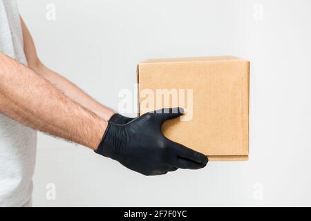 Kurierhände in medizinischen Gummihandschuhen, die Kartons halten. Lieferservice. Quarantäne. Coronavirus. Stockfoto