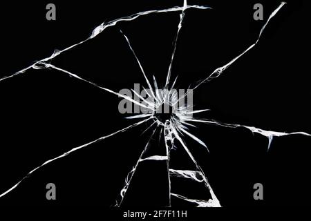 Beschädigtes Glas mit Rissen, Risse im Glas vom Schuss. Kaputtes Fenster, Textur auf schwarzem Hintergrund Stockfoto