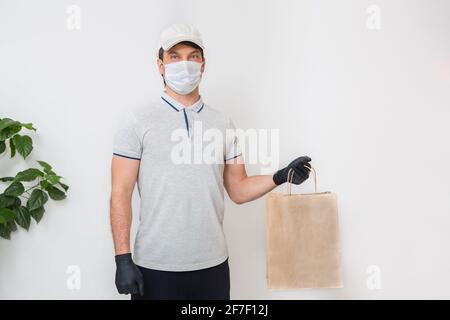 Kurier in medizinischen Gummihandschuhen und Schutzmaske mit Kartons. Lieferservice. Quarantäne. Stockfoto
