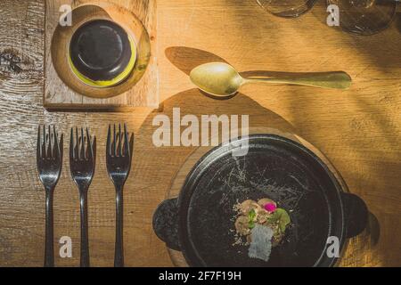 Schickes Besteck, Geschirr, Teller und anderes Zeug auf einem Tisch, mit einer Art von schickes Essen, das von oben aussieht. Stockfoto