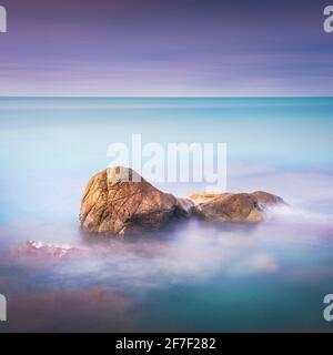 Felsen, weiches Meer und Wolken am Himmel, schöne Landschaft in Langzeitbelichtung Fotografie. Castiglioncello, Toskana, Italien. Stockfoto