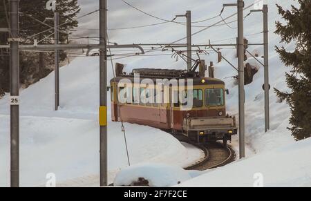 Schmalspurbahn in Murren, die Dörfer im Lauterbrunnental verbindet, nur durch eine Kurve. Im Winter gibt es viel Schnee. Stockfoto