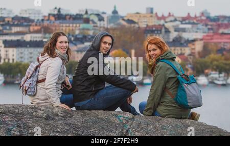 Eine Gruppe von Touristen posiert auf dem Aussichtspunkt Skinnarviksberget, weit über Stockholm. Das Stadtbild von stockholm ist im Hintergrund zu sehen. Stockfoto