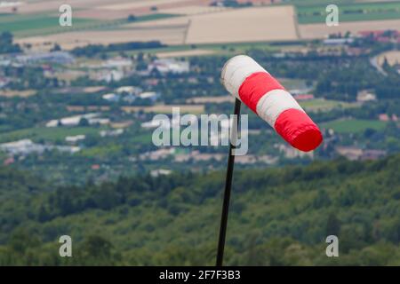 Rot-weiße Windsocke, die das stürmisch-windige Wetter am Hügel messen. Meteorologie-Messinstrument zeigt Windkraft bei Hurrikan. Gefährliche Prognose. Stockfoto