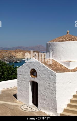 Die Kapelle des Heiligen Georg Pachymachiotis in Lindos auf Rhodos, Griechenland. Die weiße griechisch-orthodoxe Kapelle ist unter einem klaren blauen Himmel zu sehen. Stockfoto