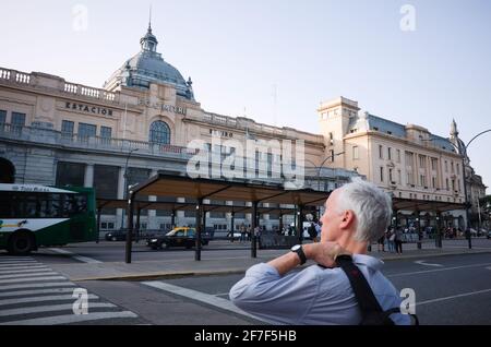 Buenos Aires, Argentinien - Januar 2020: Grauhaariger Mann mit Rucksack überquert Straße vor Bushaltestelle und Retiro Bahnhof Stockfoto
