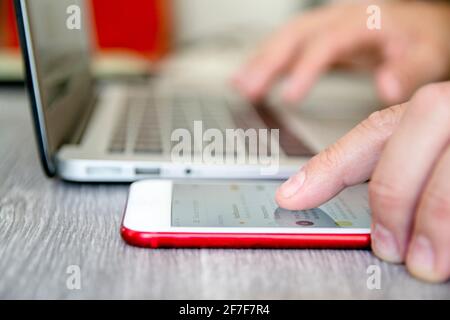 Nahaufnahme des Fingers eines Mannes, der Informationen auf seinem Smartphone konsultiert. Konzept der Telearbeit von zu Hause aus. Stockfoto