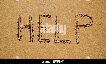 Hilfe - Inschrift auf dem Sand am Meer. Stockfoto