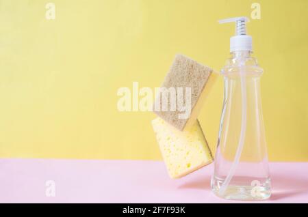 Flaches Lay mit Seifentropfer, Spülmittel, Spülmittel, Waschlappen auf pastellrosa und gelben Hintergrund. Hochwertige Fotos Stockfoto