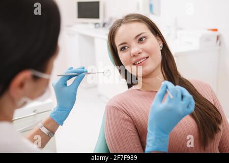 Junge, schöne Frau lächelt ihrem Zahnarzt zu und bekommt eine Zahnuntersuchung Stockfoto