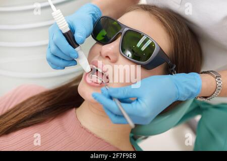 Nahaufnahme einer Frau, die eine Schutzbrille trägt und eine Zahnreinigung durch einen professionellen Hygieniker erhält Stockfoto