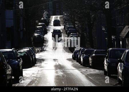 Swansea, Wales, Großbritannien - 6. Dezember 2020, von Bäumen gesäumte Stadtstraße voller geparkter Autos, hoher Kontrast Stockfoto