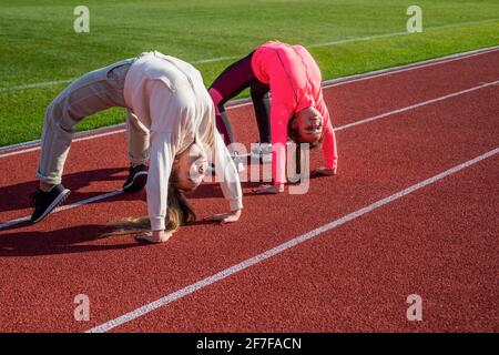 Flexible Mädchen Turnerinnen stehen in Krabbenposition auf der Leichtathletik-Strecke, Flexibilität Stockfoto