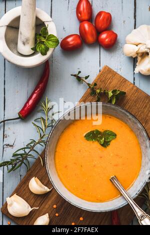 Köstliche, farbige Linsensuppe mit Herbes, Tomaten, Chili und Knoblauch auf einem grauen Tisch liegend, Draufsicht, vertikal. Stockfoto