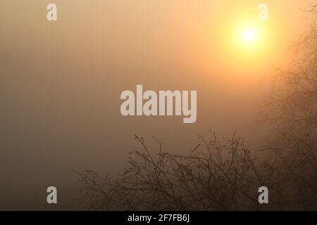 Sonnenaufgang. Die Sonne scheint an einem frühen Morgen im Frühling durch die nebligen und nebligen Wolken. Stockfoto