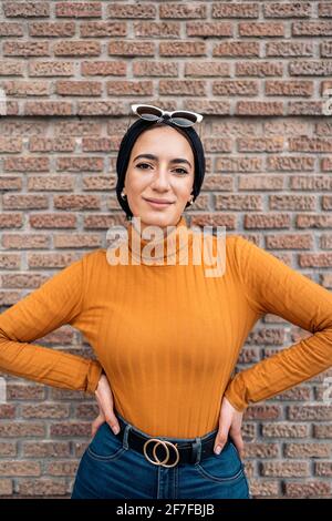 Hübsche junge muslimische Frau mit schwarzem Kopftuch, lächelnd und mit Blick auf die Kamera. Stockfoto