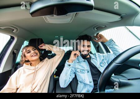 Fröhliches, fröhliches Paar, das Spaß hat, während es in einem Auto sitzt Stockfoto