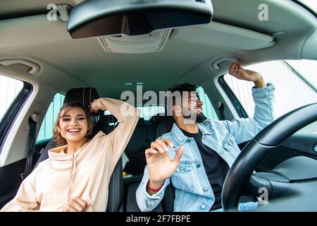 Fröhliches, fröhliches Paar, das Spaß hat, während es in einem Auto sitzt Stockfoto