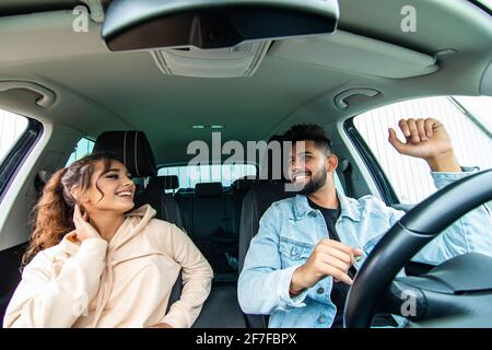 Fröhliches, fröhliches Paar, das Spaß hat, während es in einem Auto sitzt Stockfoto