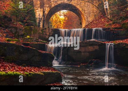 Kaskade der Wasserfälle unter einer Steinbrücke im Herbst Wald Stockfoto