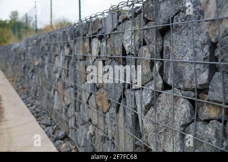 Nahaufnahme einer Stützmauer aus Steinen. Eine Mauer namens Gabion. Stockfoto