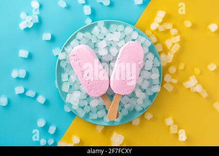 Erdbeerpopsicles und zerkleinertes Eis auf blauem Teller Stockfoto