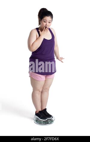 Übergewichtige junge Frau, die sich auf einer Waage wiegt Stockfoto