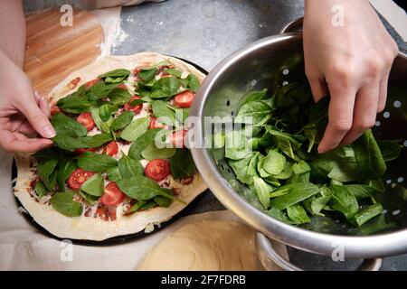 Pizza mit Käse, Tomaten, Spinat und Räucherwurst Stockfoto