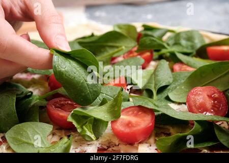 Pizza mit Käse, Tomaten, Spinat und Räucherwurst Stockfoto