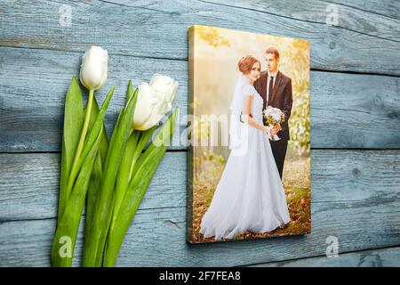Foto auf Leinwand gedruckt. Leinwanddruck mit weißen Blumen auf hellblauem Holzhintergrund. Hochzeits-Portrait und Blumenstrauß aus Tulpen, Fotografie-Stretche Stockfoto