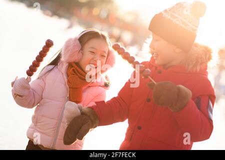 Glückliche Geschwister essen kandierte Hagebutten im Freien Stockfoto