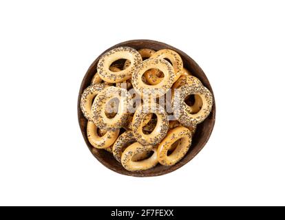 Baranka sushka mit Mohnsamen bedeckt. Osteuropäischer salziger Plätzchen-Snack in brauner natürlicher Kokosnussschale, flache Lay-Ansicht, isoliert auf Weiß. Stockfoto