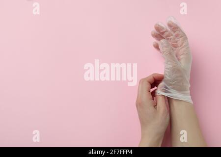 Weibliche Hände in Einweghandschuhen auf rosa Hintergrund Stockfoto