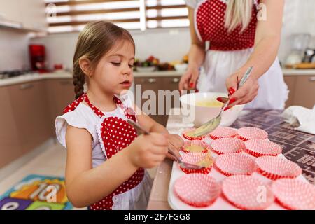 Kleines Mädchen im Vorfeld, das ihrer Mutter in der Küche half Stockfoto